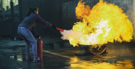 Femeie stingand incendiu. img reprezentativ pentru articol Ce trebuie să știi despre stingătoare de incendiu în 2025?